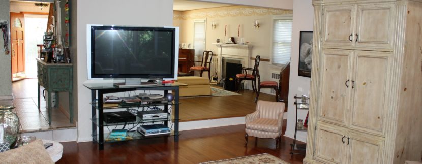 A living room with a television and a rug.